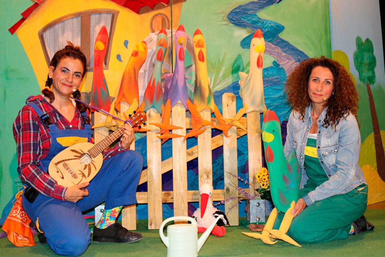 Dorotea y Renata en el escenario  sentadas con una guitarra y un gallo